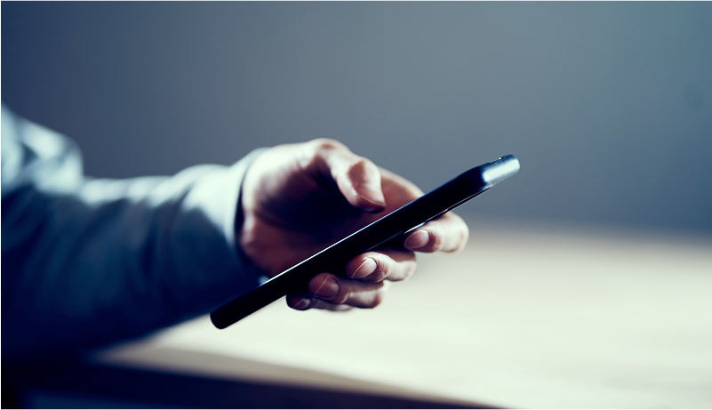 片手で黒いスマートフォンを持っている様子