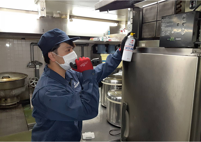 業務用厨房で害虫駆除のスプレーを使用している様子。